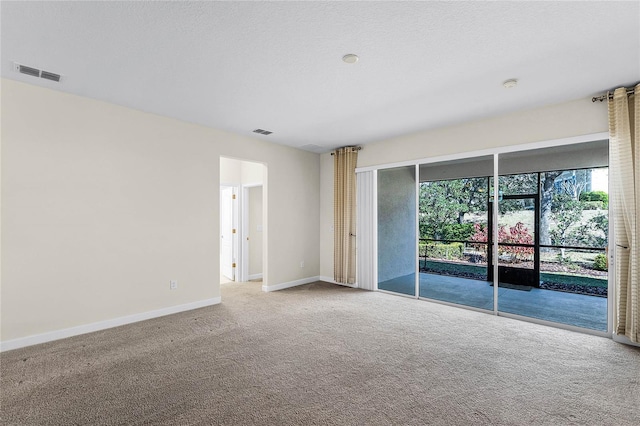 unfurnished room featuring a textured ceiling, carpet, visible vents, and baseboards