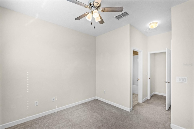 carpeted empty room featuring ceiling fan, visible vents, and baseboards