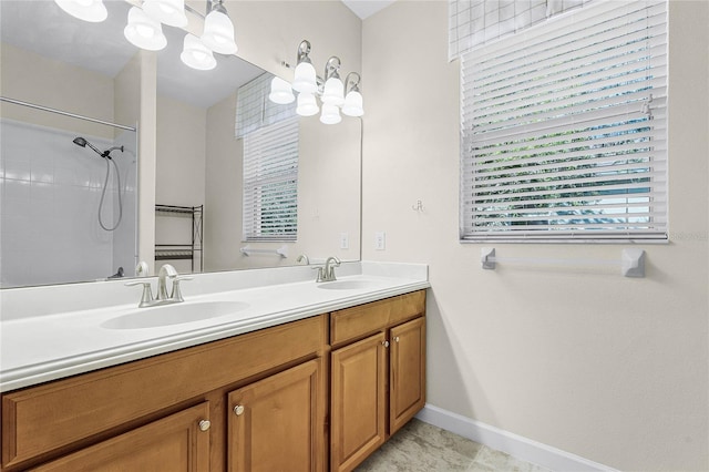 bathroom featuring walk in shower, a sink, baseboards, and double vanity