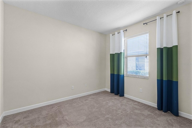 empty room with a textured ceiling, carpet floors, and baseboards