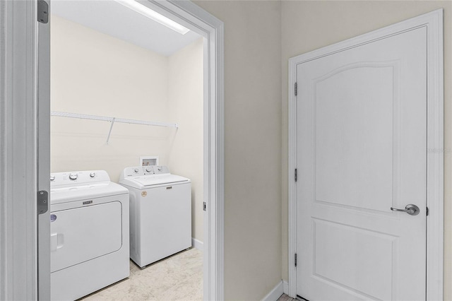 clothes washing area with baseboards, laundry area, and washer and dryer