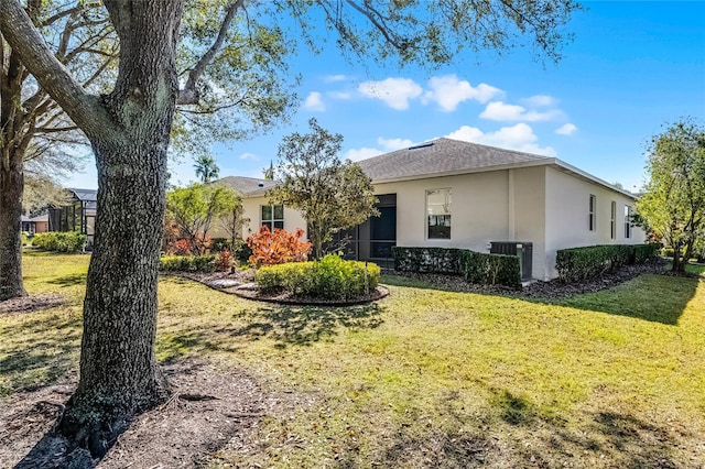 view of front of property featuring a front yard, central AC, and stucco siding