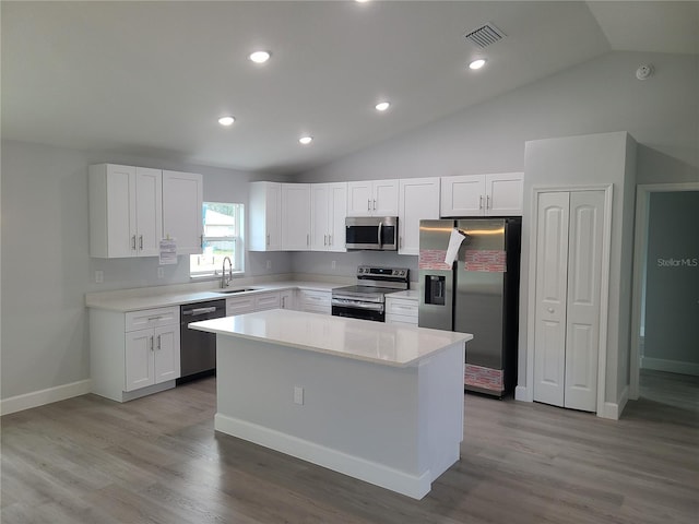 kitchen with stainless steel appliances, white cabinetry, visible vents, light countertops, and a center island