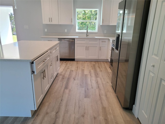 kitchen featuring stainless steel appliances, light countertops, a sink, and white cabinetry