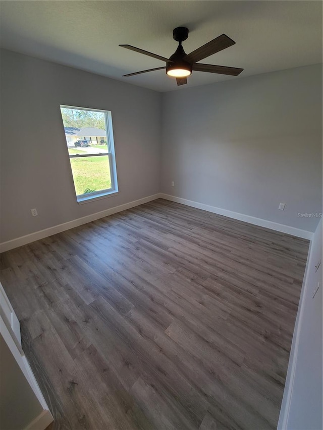 empty room featuring ceiling fan, wood finished floors, and baseboards