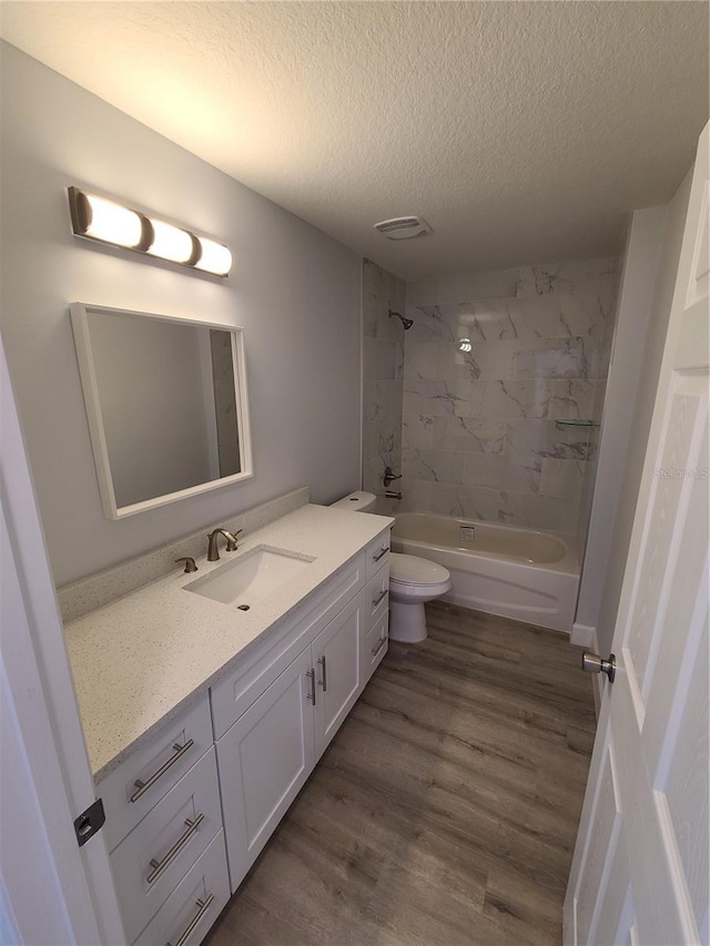 bathroom with toilet, shower / bathtub combination, wood finished floors, a textured ceiling, and vanity