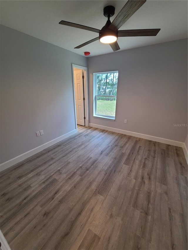 unfurnished room featuring a ceiling fan, baseboards, and wood finished floors