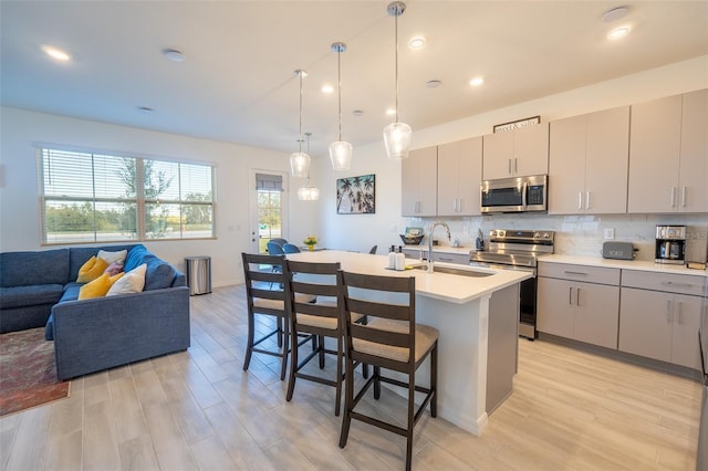 kitchen with stainless steel appliances, light countertops, backsplash, a sink, and a kitchen breakfast bar