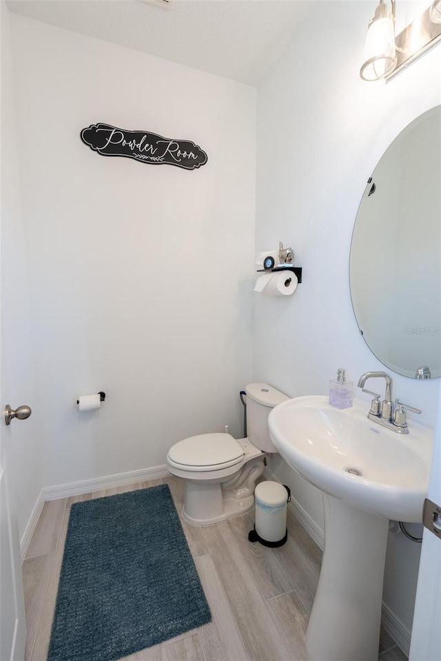 bathroom with wood finished floors, toilet, and baseboards