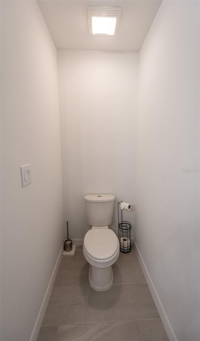 bathroom featuring tile patterned flooring, toilet, and baseboards