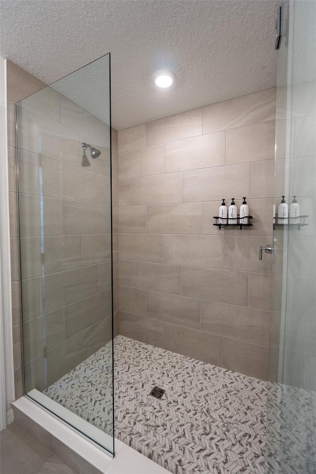 full bath featuring a textured ceiling and tiled shower