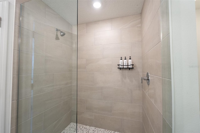 full bathroom with tiled shower and a textured ceiling