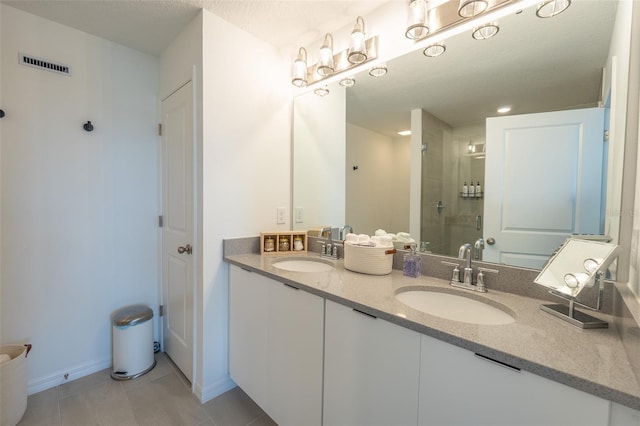 bathroom featuring a stall shower, tile patterned flooring, a sink, and visible vents