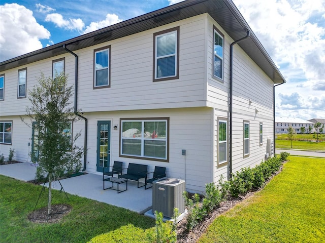 back of property with central AC unit, a lawn, and a patio