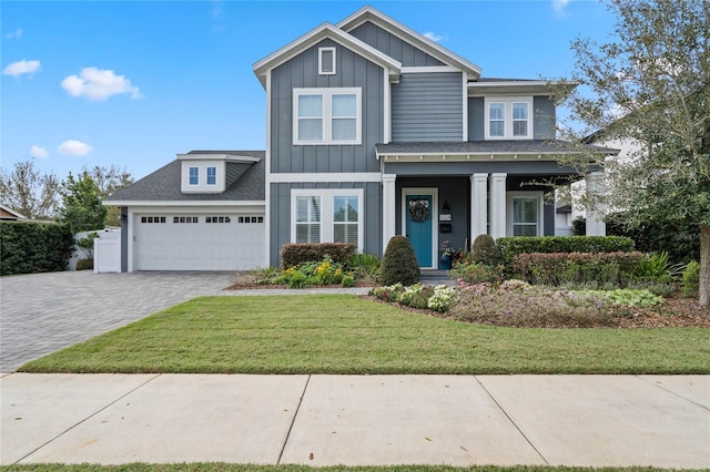 view of front of property featuring an attached garage, a shingled roof, decorative driveway, a front lawn, and board and batten siding