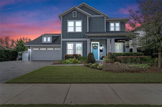 traditional home featuring a garage, decorative driveway, board and batten siding, and a lawn