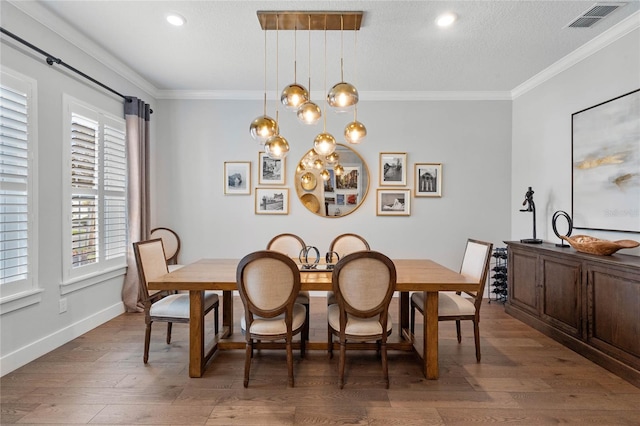 dining area featuring a textured ceiling, ornamental molding, visible vents, and light wood-style floors