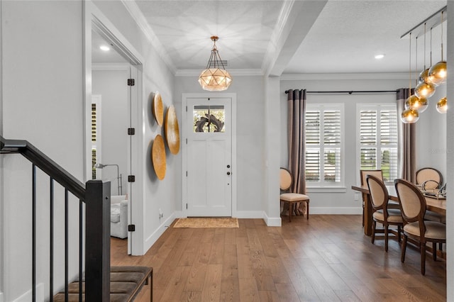 foyer featuring hardwood / wood-style flooring, plenty of natural light, ornamental molding, and baseboards