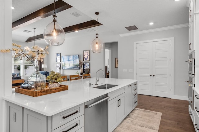 kitchen featuring wood finished floors, appliances with stainless steel finishes, beamed ceiling, and a sink