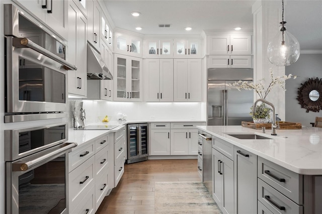 kitchen featuring under cabinet range hood, beverage cooler, stainless steel appliances, a sink, and visible vents