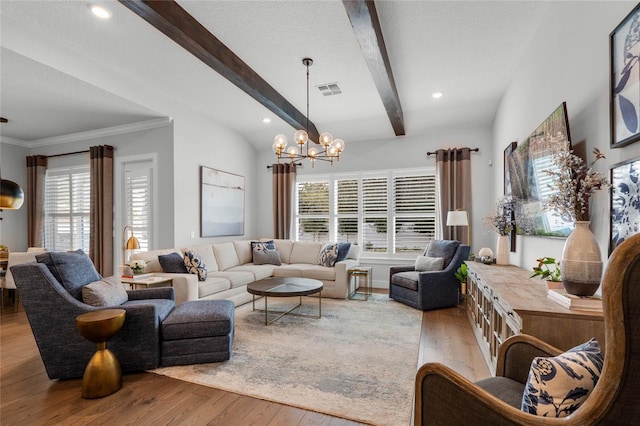 living area with visible vents, wood finished floors, beam ceiling, and a chandelier