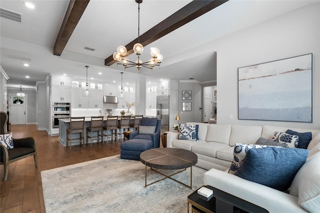 living area featuring a chandelier, beamed ceiling, wood finished floors, and visible vents