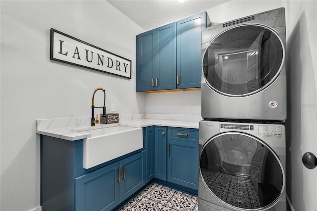 washroom with cabinet space, light tile patterned floors, stacked washer / dryer, a textured ceiling, and a sink