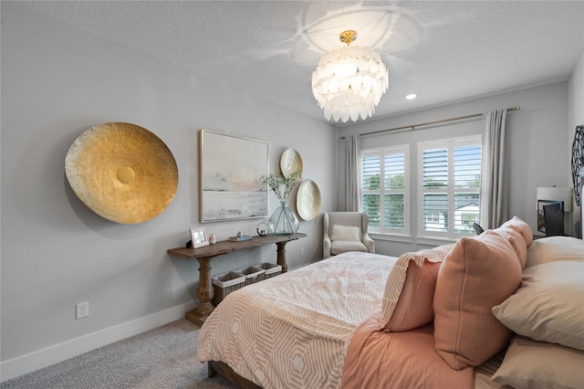 carpeted bedroom with a chandelier, a textured ceiling, and baseboards