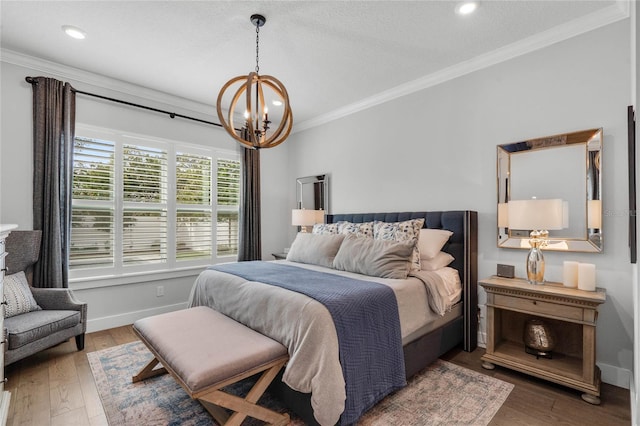 bedroom featuring a chandelier, ornamental molding, wood finished floors, and baseboards