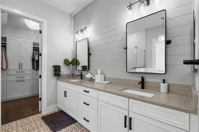 full bath with double vanity, wood finished floors, a spacious closet, and a sink