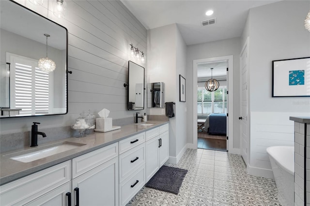 bathroom with double vanity, visible vents, a sink, and ensuite bathroom