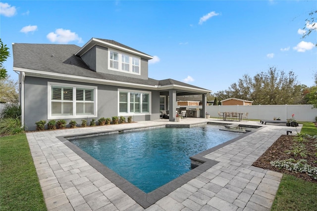 back of house with stucco siding, a fenced backyard, an outdoor kitchen, and a patio