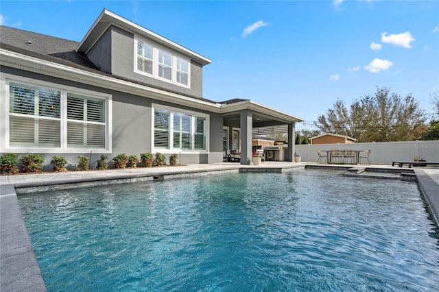 view of swimming pool featuring a fenced in pool, fence, an outdoor kitchen, and a patio