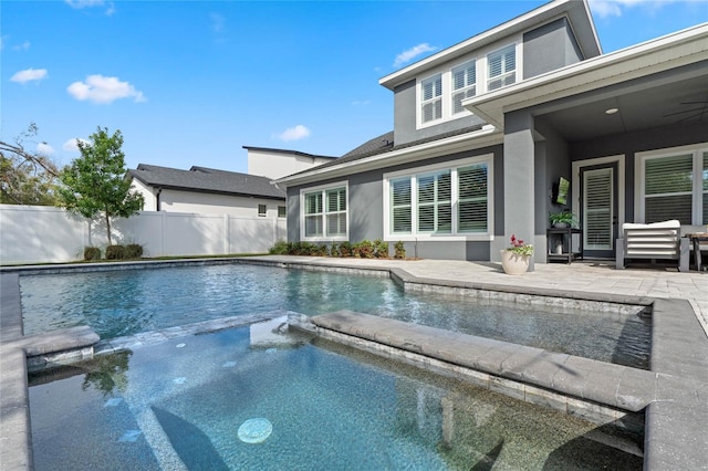 view of pool with a patio, fence, and a pool with connected hot tub