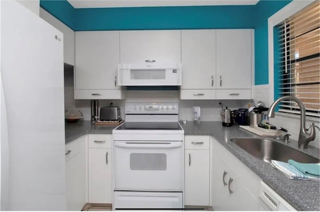 kitchen with white appliances, white cabinetry, and a sink