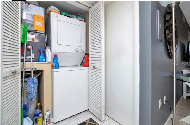 washroom featuring stacked washer and clothes dryer, light tile patterned floors, and laundry area