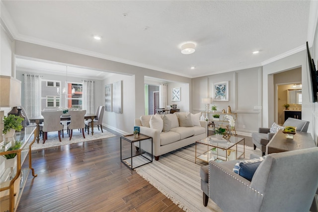 living room with baseboards, a textured ceiling, ornamental molding, and wood finished floors