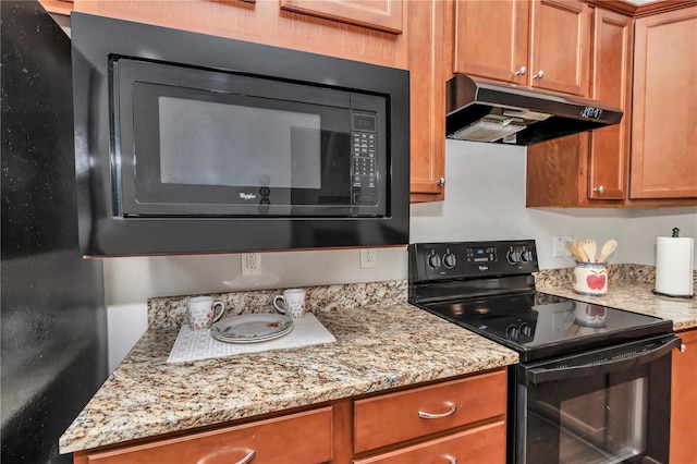 kitchen featuring black appliances, light stone counters, brown cabinets, and under cabinet range hood