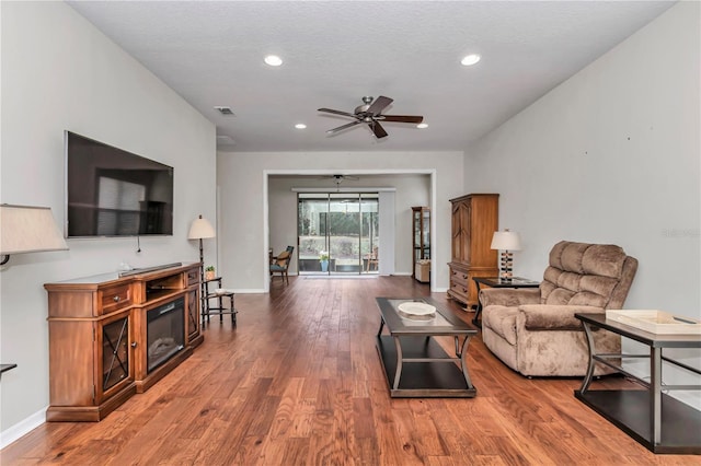 living room with a ceiling fan, recessed lighting, baseboards, and wood finished floors