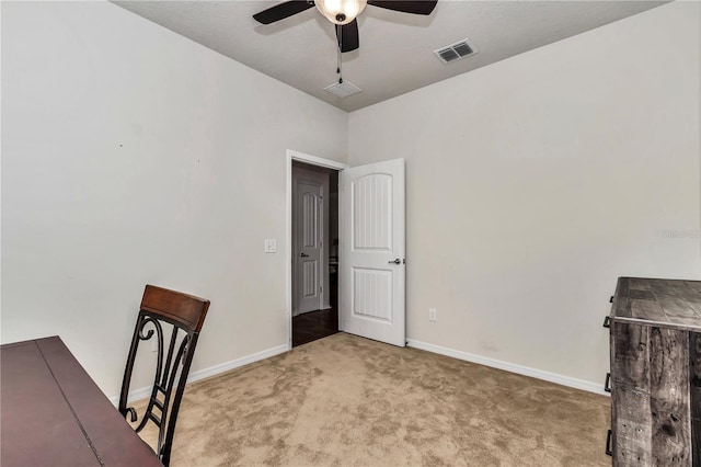 unfurnished office featuring carpet floors, baseboards, visible vents, and a ceiling fan