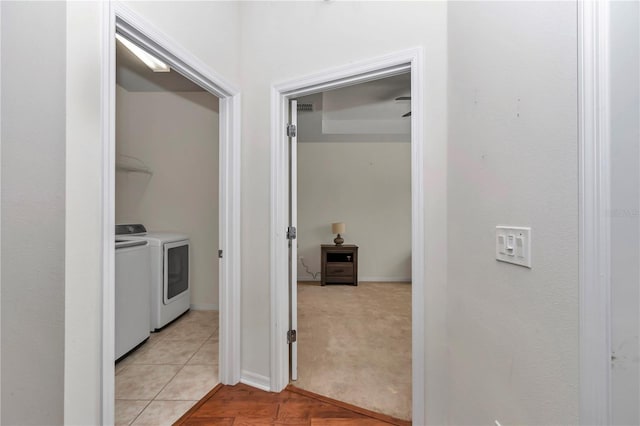 corridor featuring light tile patterned floors, visible vents, light carpet, washer and dryer, and baseboards