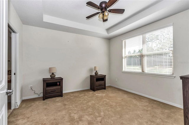 bedroom featuring light carpet, baseboards, and a tray ceiling