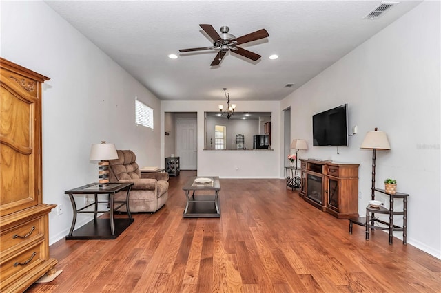 living room featuring recessed lighting, visible vents, wood finished floors, baseboards, and ceiling fan with notable chandelier