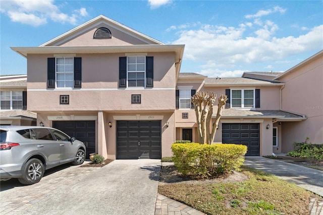 view of front of property featuring driveway, an attached garage, and stucco siding