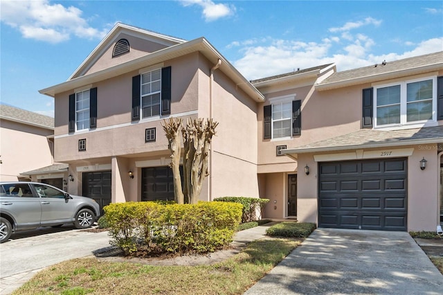 multi unit property with driveway, an attached garage, and stucco siding