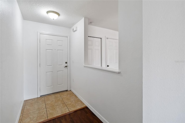 doorway featuring a textured ceiling, baseboards, and tile patterned floors