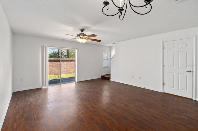 unfurnished room with ceiling fan with notable chandelier, dark wood-style flooring, a textured ceiling, and baseboards