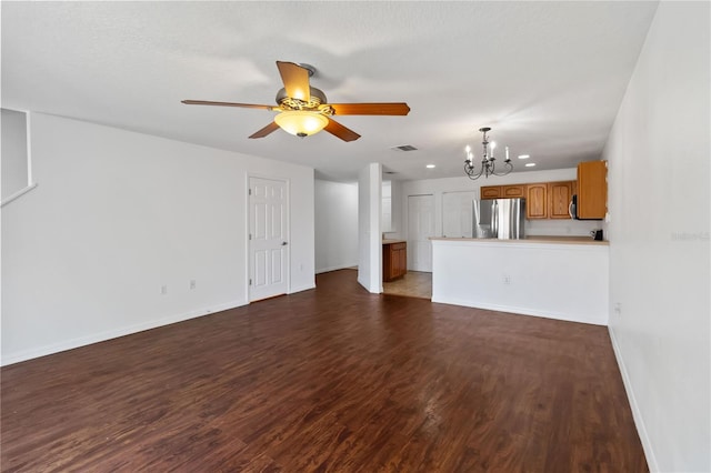 unfurnished living room featuring ceiling fan with notable chandelier, dark wood-type flooring, visible vents, and baseboards