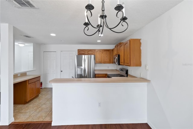 kitchen with stainless steel appliances, visible vents, light countertops, and a peninsula