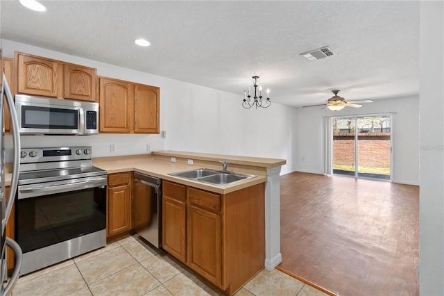 kitchen featuring a peninsula, a sink, visible vents, light countertops, and appliances with stainless steel finishes